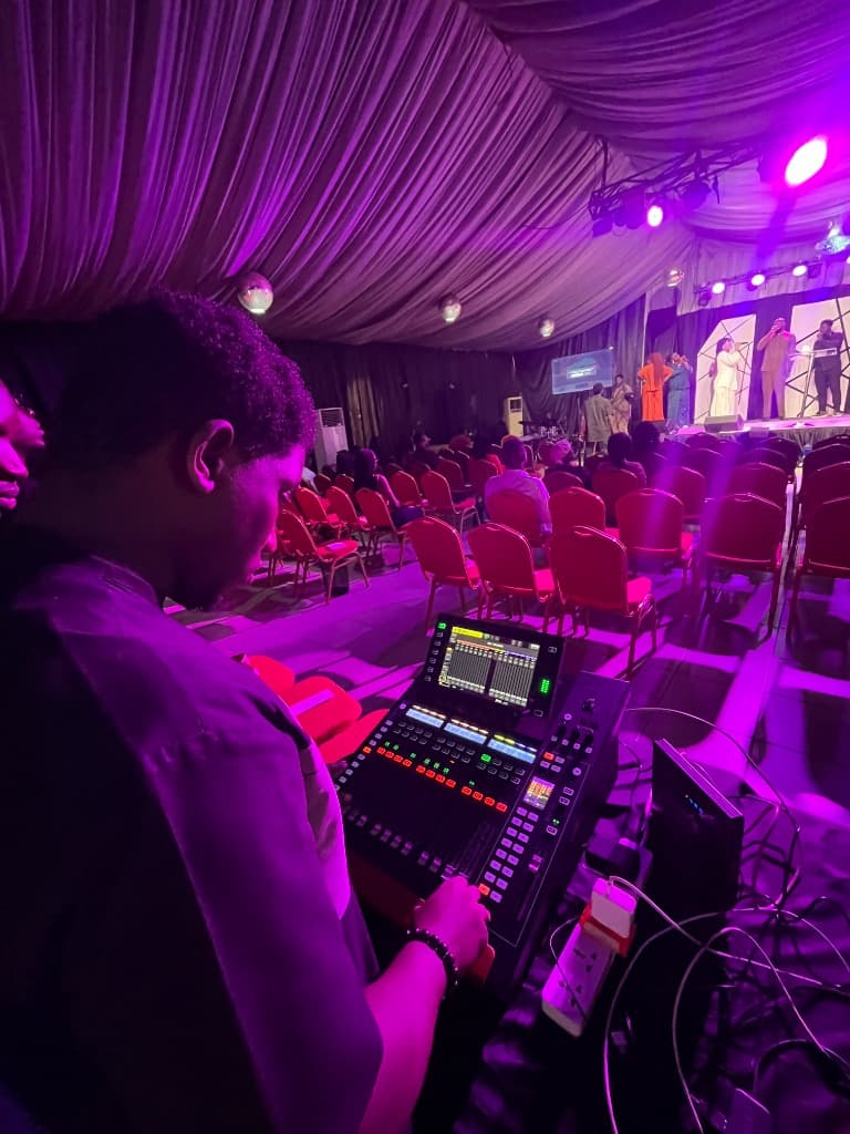 Emordi Akachukwu operating a digital mixing console at a live event